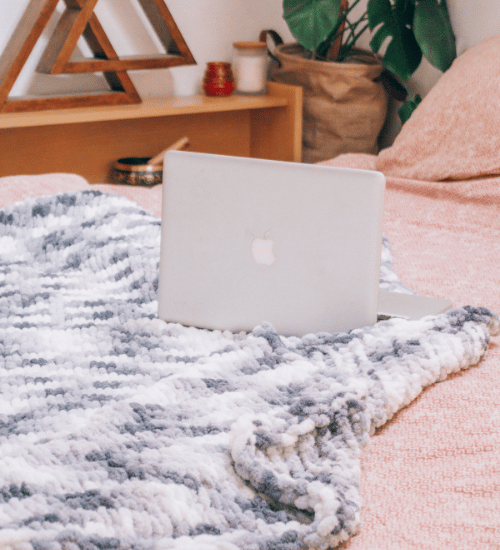 Macbook on a bed in a bedroom on a throw